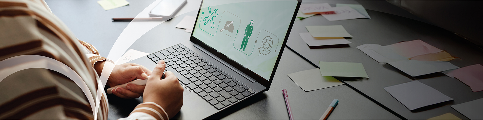 A person sitting at a desk using a laptop that displays 4 icons that symbolises a variety of topics.