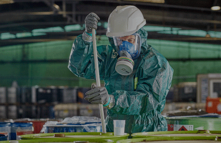 Image of text and a worker wearing chemical protective clothing handling chemicals