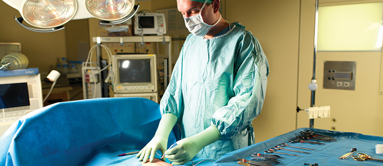 Image of a hospital surgeon in full healthcare personal protective equipment about to start a surgical procedure in the operating room.