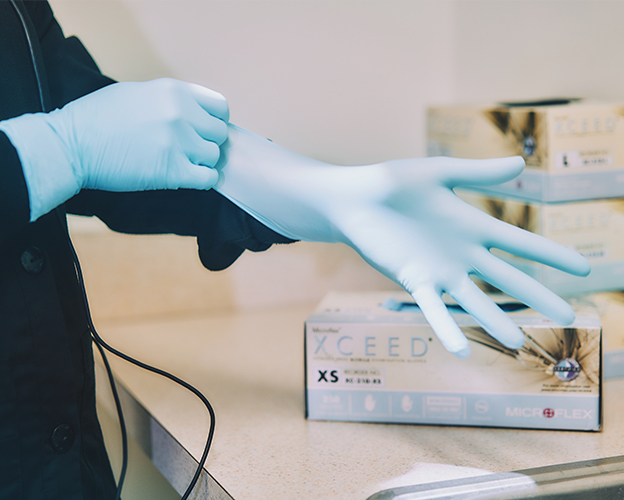 An image of a dental professional donning a MICROFLEX XCEED glove