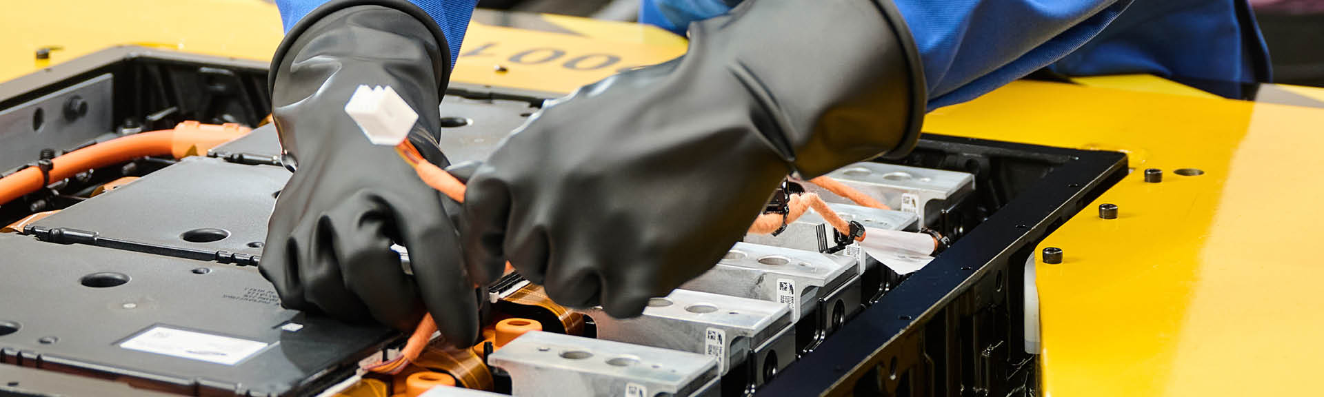 Image of a worker wearing chemical gloves while handling lithium-ion batteries in a workplace to protect himself from chemical hazards