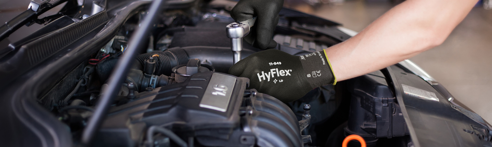 Automotive industrial worker wearing HyFlex gloves while working to demonstrate durability of Ansell glove coating