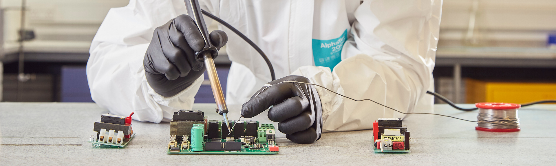 Industrial worker wearing MICROFLEX ESD gloves and AlphaTec protective clothing while working with electricity in manufacturing environment
