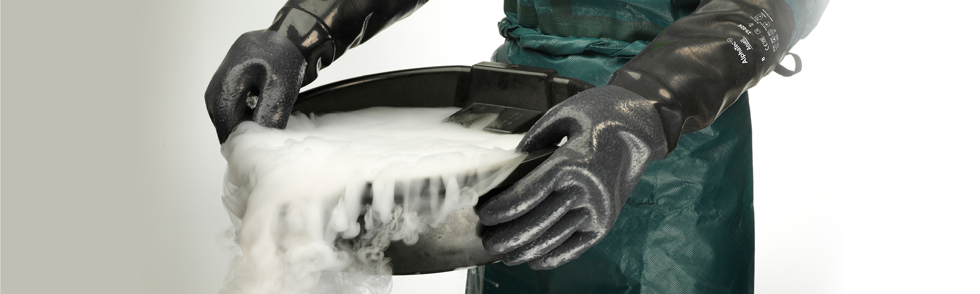 Industrial worker wearing AlphaTec chemical gloves and apron while handling dry ice in manufacturing environment