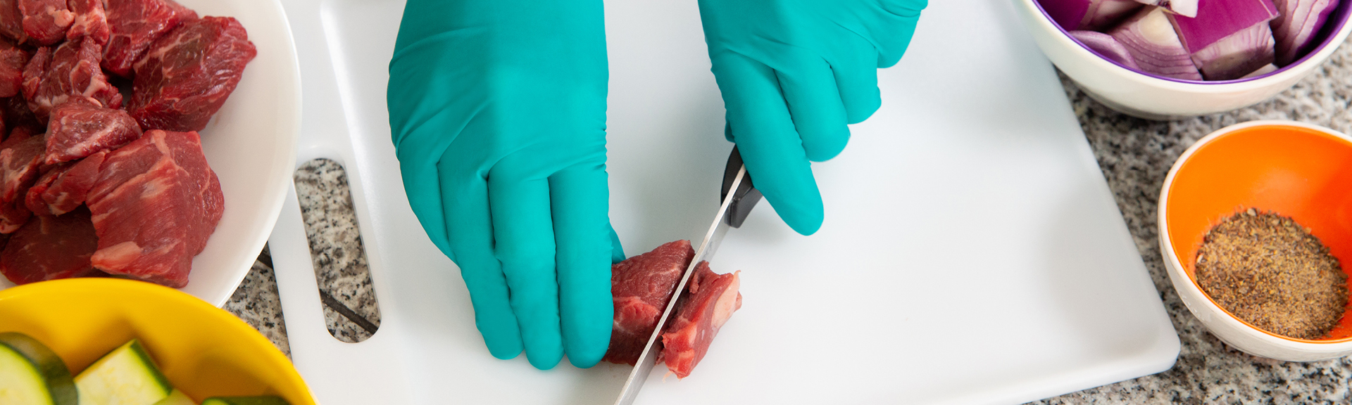 Restaurant worker wearing MICROFLEX disposable gloves while handling raw food and sharp object for food preparation