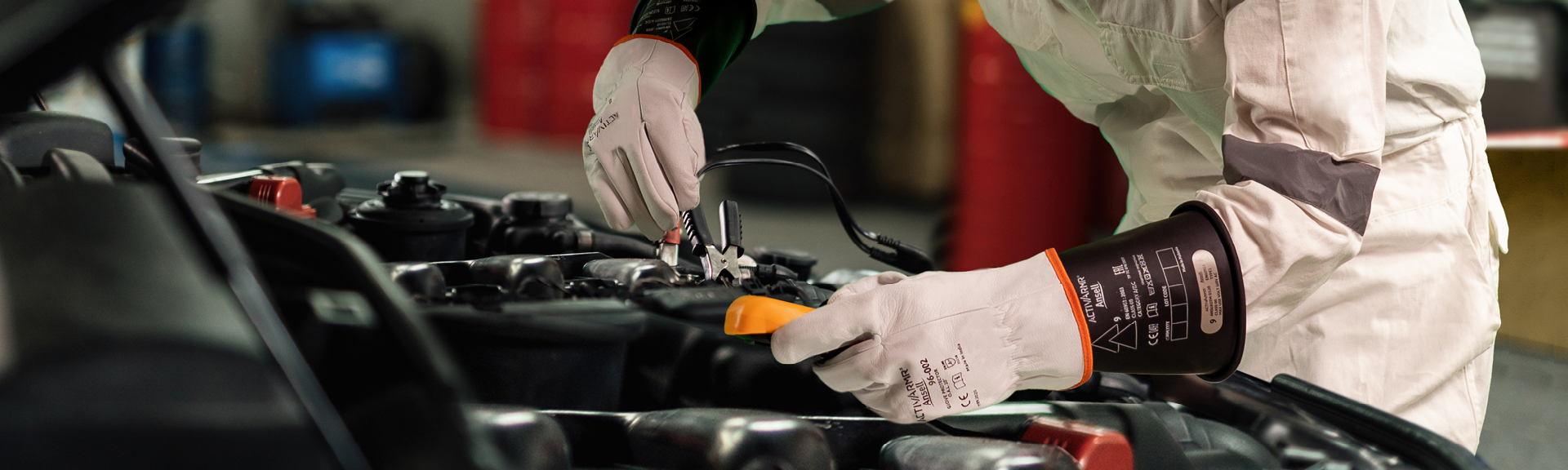 Electric vehicle and battery manufacturing work environment with industrial worker performing maintenance while wearing full electrical PPE