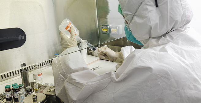 Image of a lab worker in full PPE while handling chemical