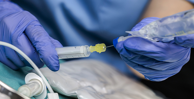 Image of a healthcare worker wearing gloves while administering fluid medication