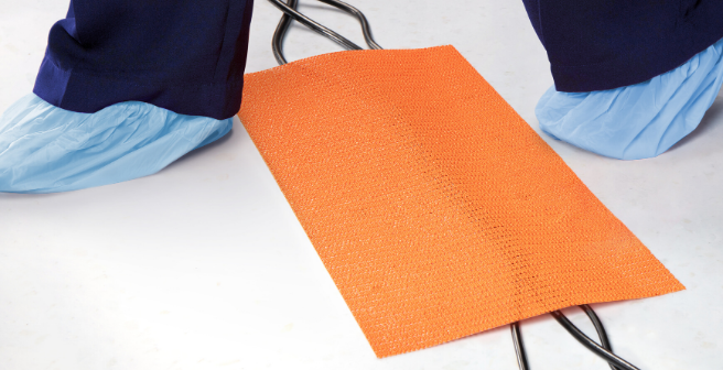 Person in sterile booties stepping over O.R. cords covered by trip-no-more