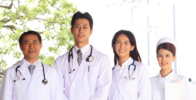 Healthcare workers standing in an outdoor group shot looking happy and confident while dressed in uniform for public hospitals in Japan