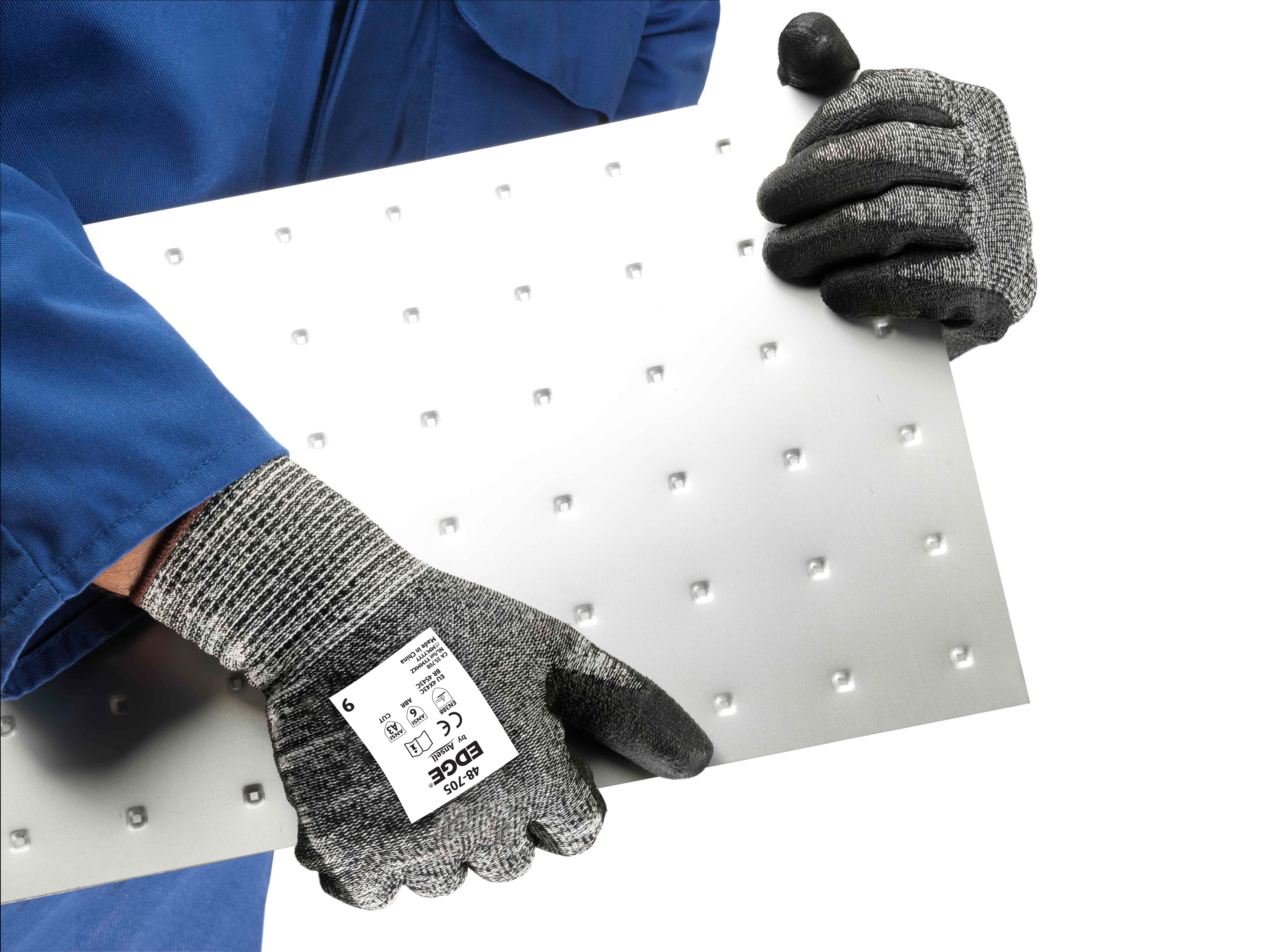 Operator wearing EDGE® 48-705 mechanical gloves handles a steel sheet, ensuring safe grip and careful positioning during transport.