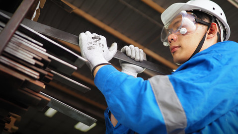 Operator wearing EDGE® 48-711 mechanical gloves handles a steel axle, ensuring safe grip and careful positioning during transport.