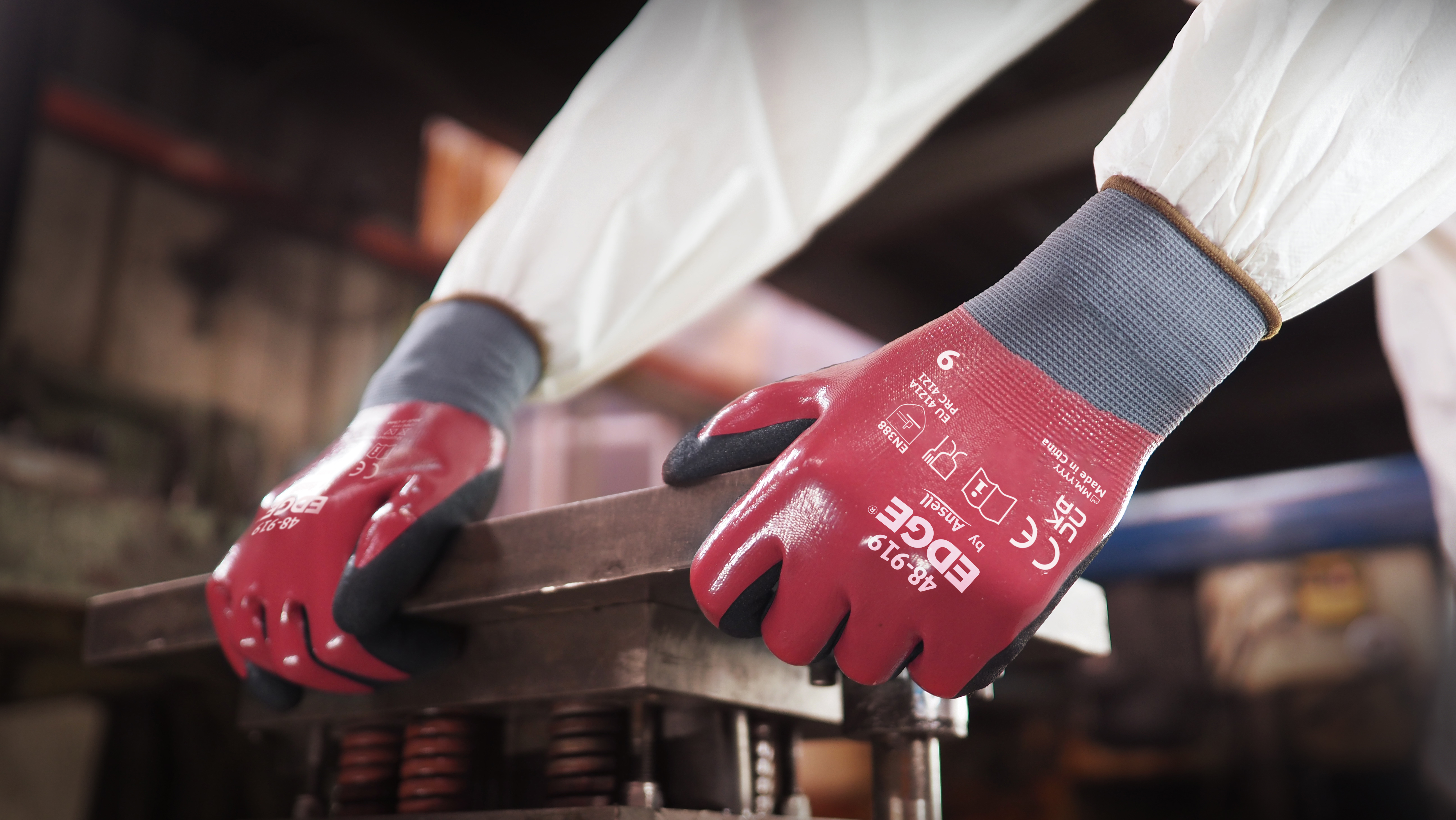 Worker wearing EDGE® 48-919 mechanical gloves engages in metallurgy tasks, handling metal materials with precision and safety