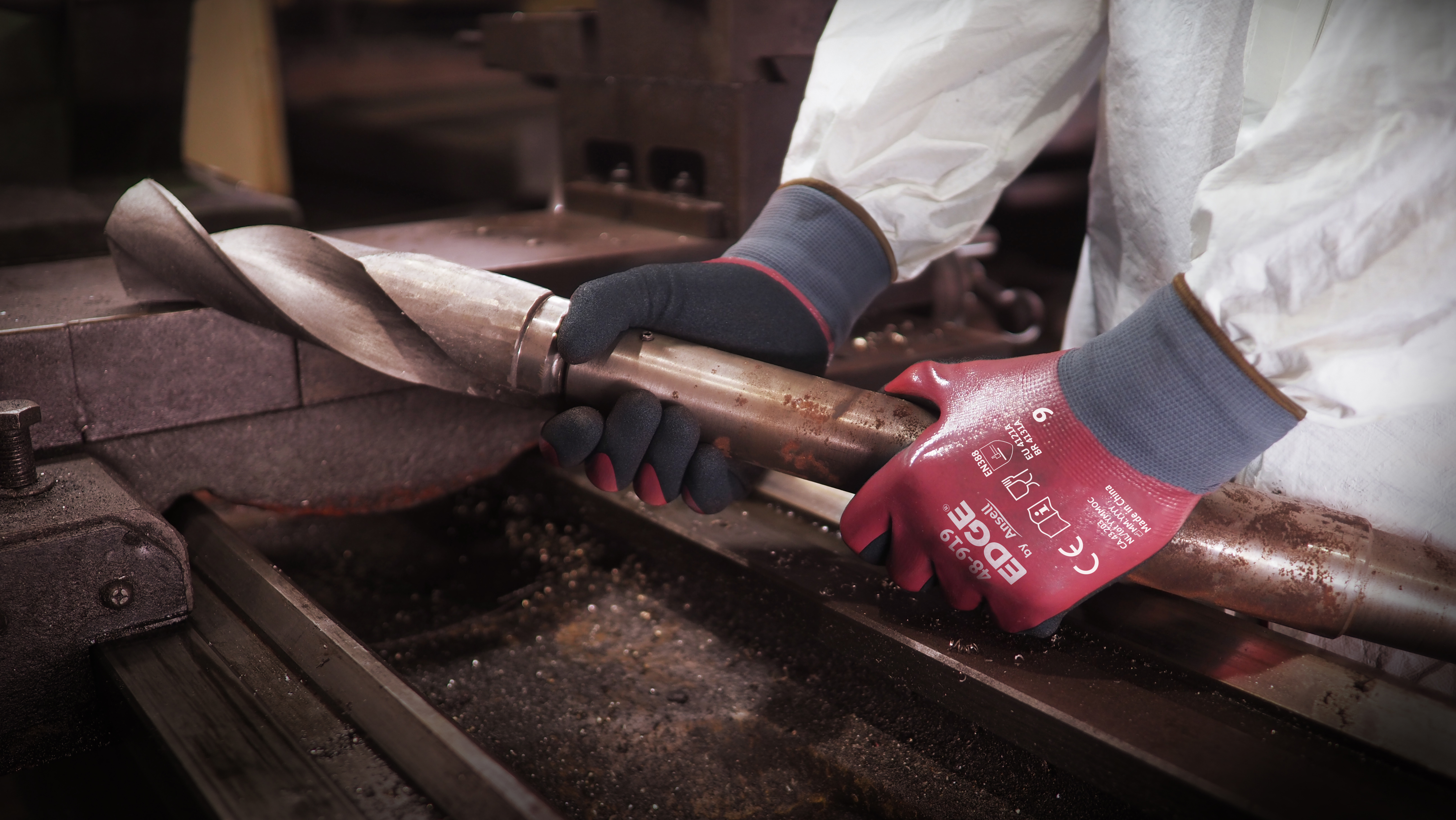 Worker wearing EDGE® 48-919 mechanical gloves engages in metallurgy tasks, handling metal materials with precision and safety