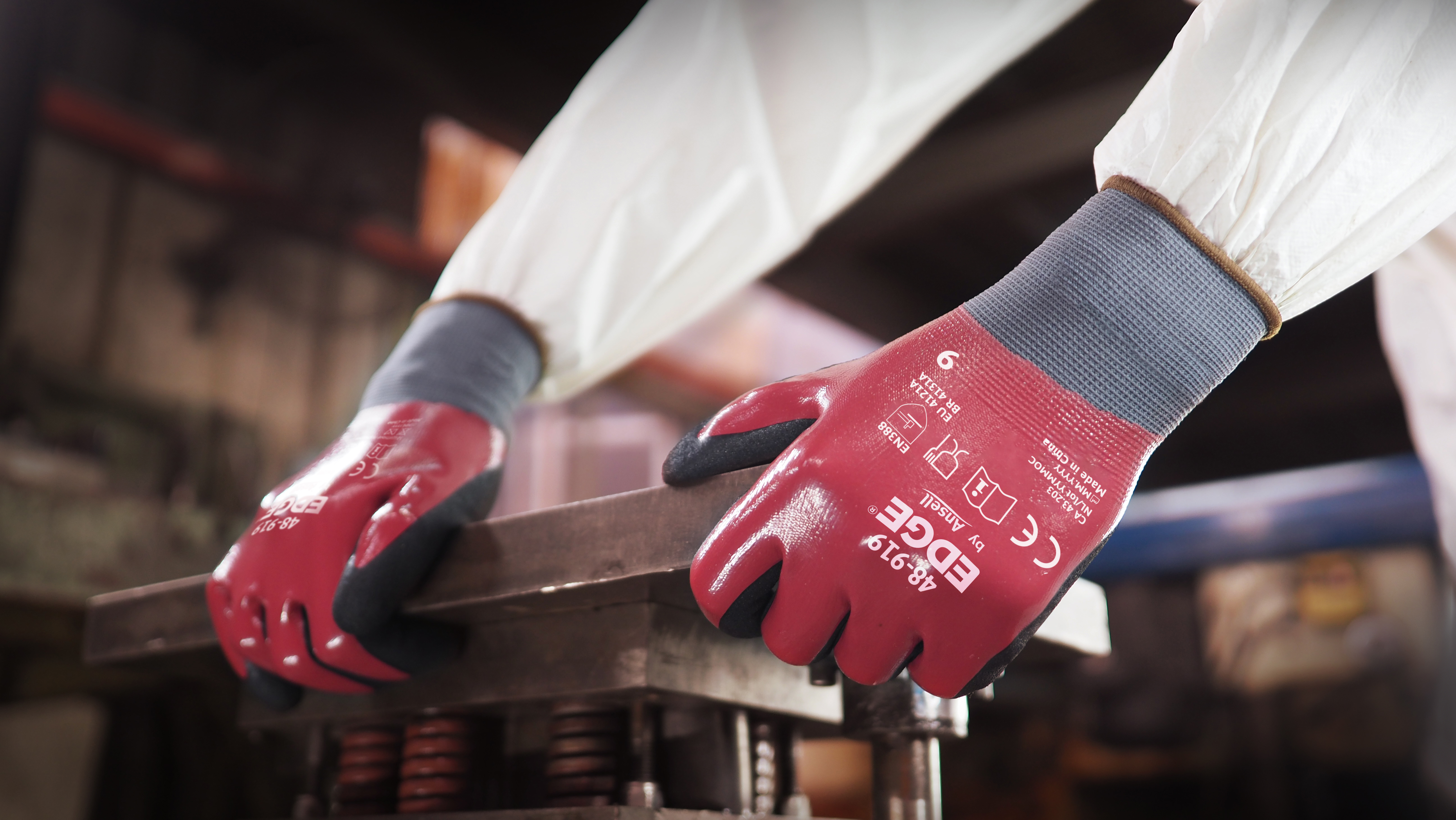 Worker wearing EDGE® 48-919 mechanical gloves engages in metallurgy tasks, handling metal materials with precision and safety