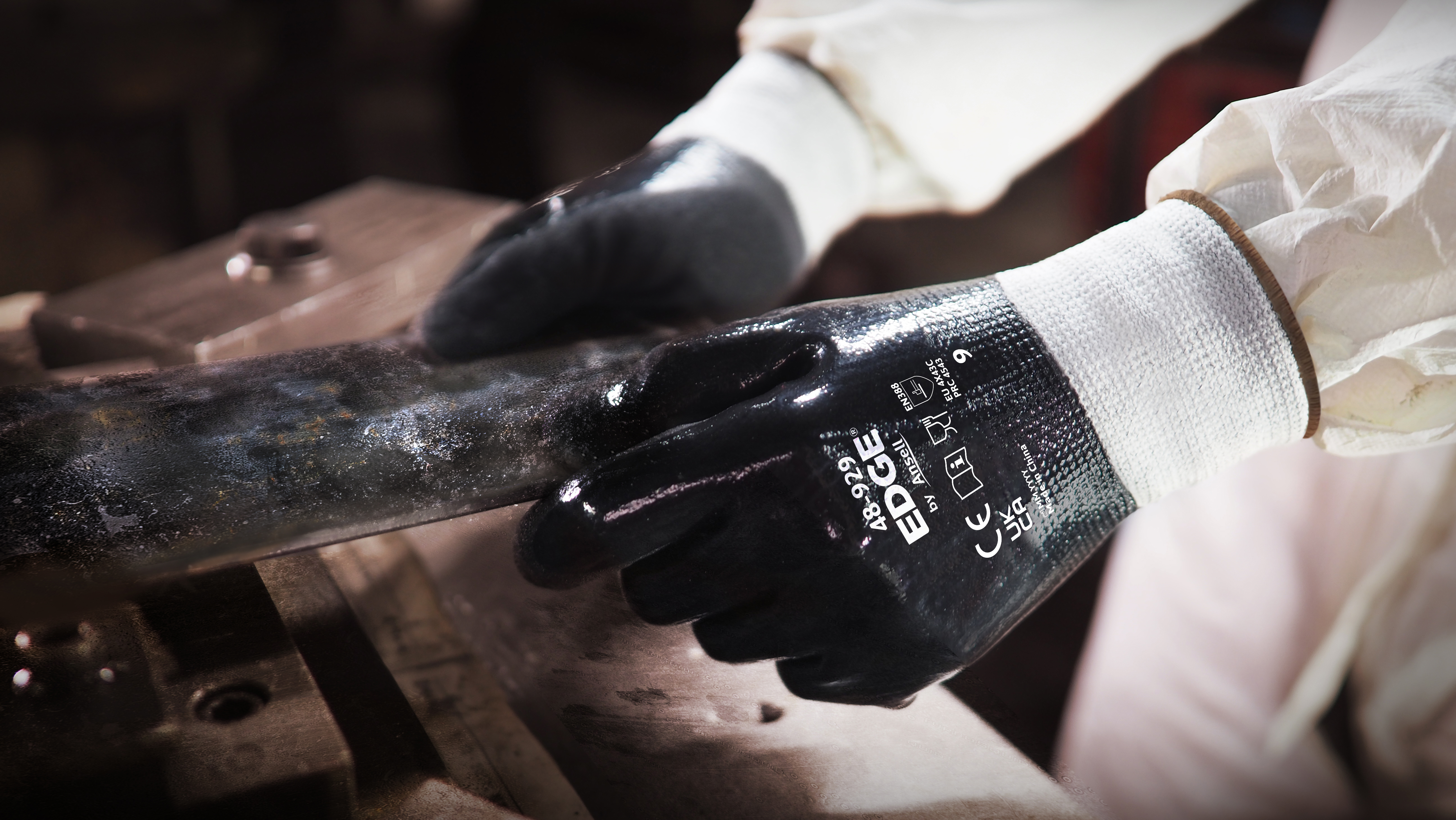 Worker wearing EDGE® 48-929 mechanical gloves engages in metallurgy tasks, handling metal materials with precision and safety.