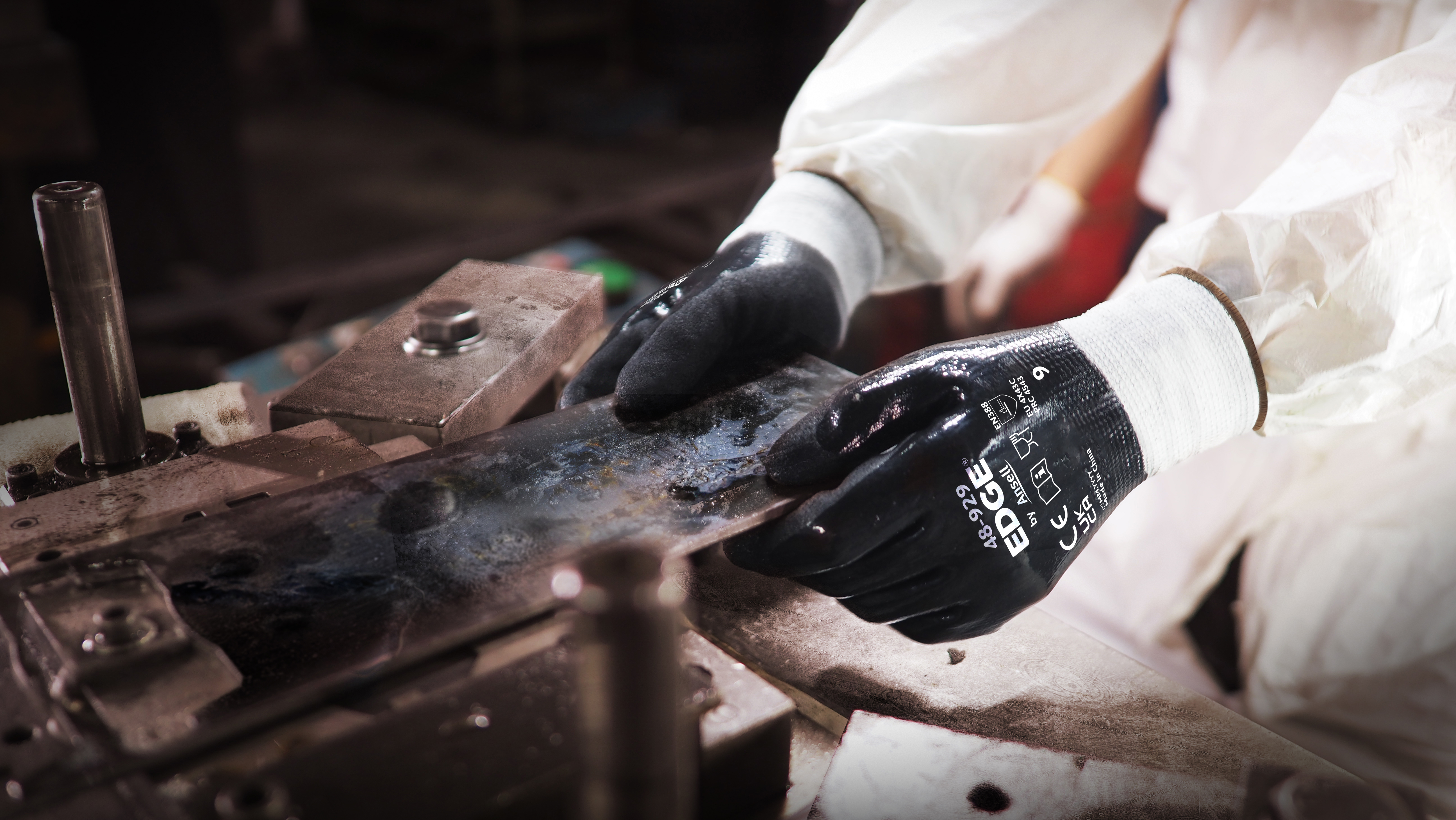 Worker wearing EDGE® 48-929 mechanical gloves engages in metallurgy tasks, handling metal materials with precision and safety.