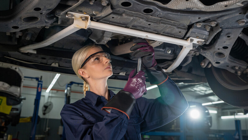 Mechanic wearing mechanical EDGE 48-393 gloves works on a car engine, ensuring precision and safety.