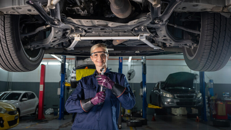 Mechanic wearing mechanical EDGE 48-393 gloves works on a car engine, ensuring precision and safety.