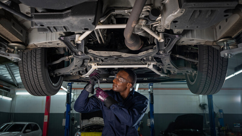 Mechanic wearing mechanical EDGE 48-393 gloves works on a car engine, ensuring precision and safety.