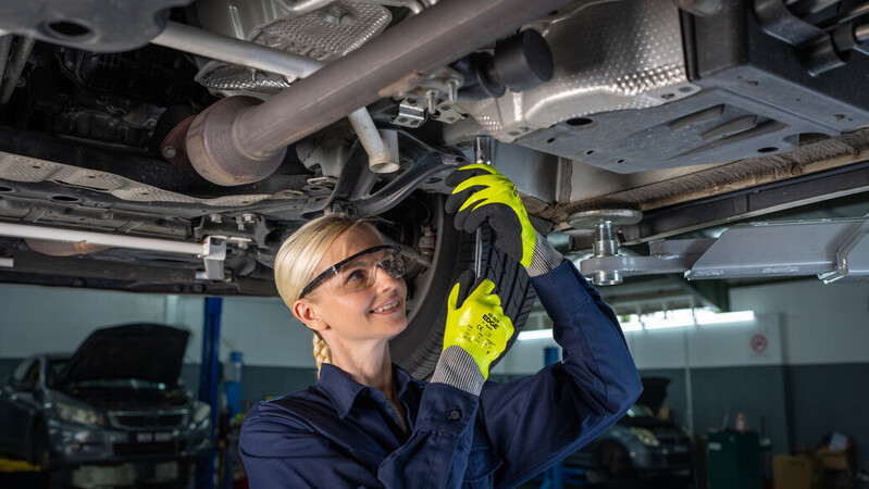 Mechanic wearing EDGE 48-969 mechanical gloves works on a car engine, ensuring precision and safety.