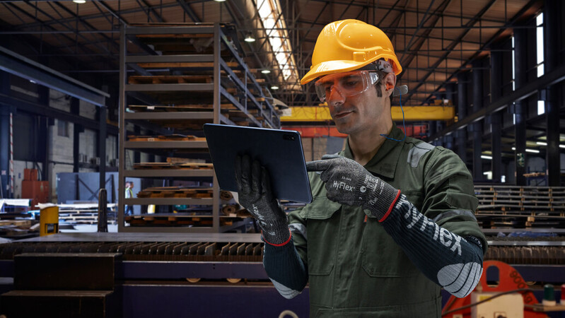 Worker checks orders on a tablet in a warehouse while wearing HyFlex® 11-543 mechanical gloves for safety and precision