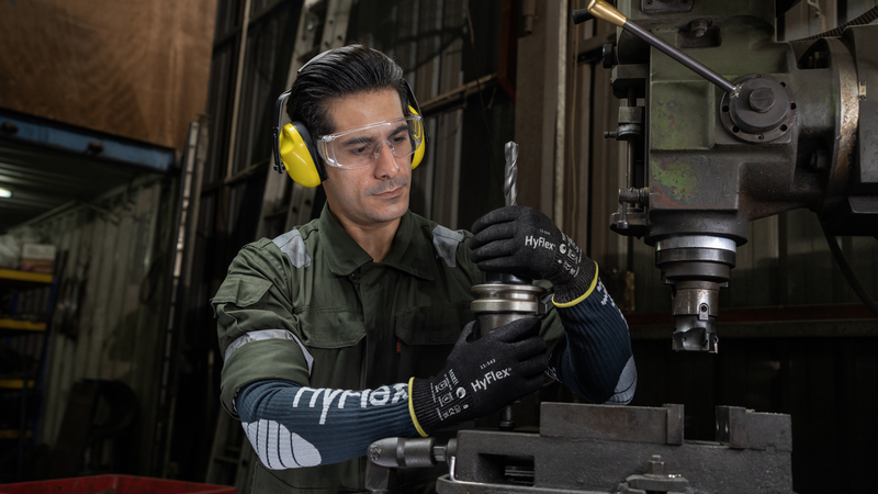Worker operates machinery while wearing HyFlex® 11-543 mechanical gloves, ensuring safe and precise handling in an industrial setting