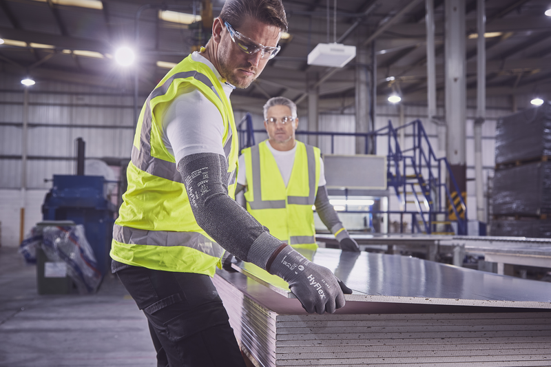 Operators wearing HyFlex® 11-581 mechanical gloves handle a panel, ensuring safe grip and careful positioning during transport