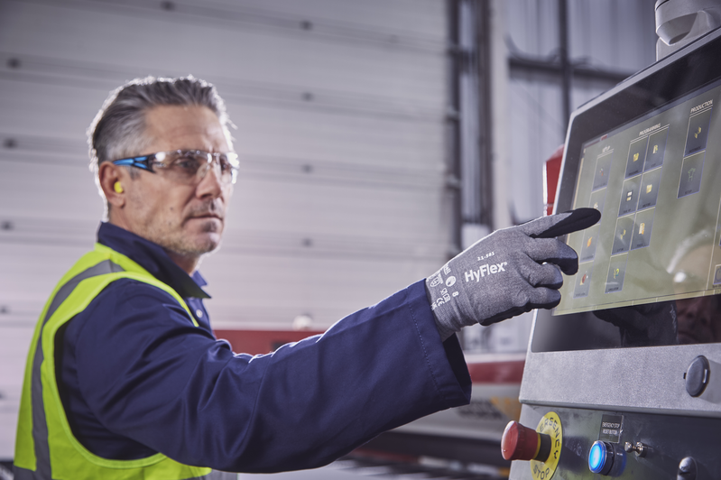 Worker wearing HyFlex® 11-581 mechanical gloves operates a computer to review tool settings, ensuring safety and efficient adjustments