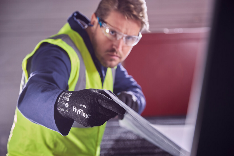 Operator wearing HyFlex® 11-591 mechanical gloves handles a panel, ensuring safe grip