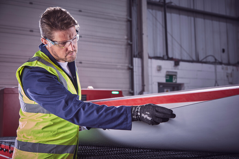 Operator wearing HyFlex® 11-591 mechanical gloves handles a panel, ensuring safe grip