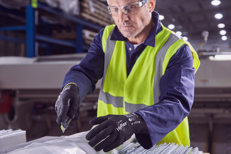 Worker wearing HyFlex® 11-591 mechanical gloves unwraps panels carefully, ensuring safety and precision in handling materials