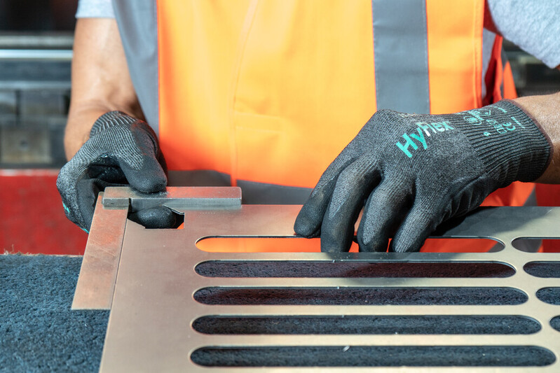 Worker handling sharp-edged metal sheet while wearing HyFlex 11-594 gloves for cut protection and grip