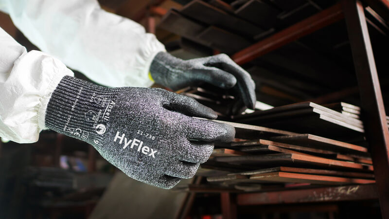 A worker wearing HyFlex 11-738 gloves extracting an iron bar from a iron stack