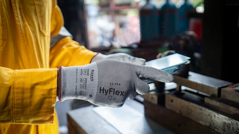 Worker wearing HyFlex® 11-754 mechanical gloves engages in metallurgy tasks, handling metal materials with precision and safety.