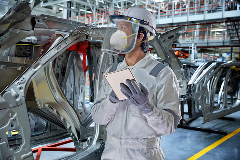 Worker uses a tablet with HyFlex® 11-754 mechanical gloves to adjust machine engine settings, maintaining control and accuracy