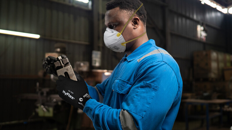 Worker uses a tablet with HyFlex® 11-757 mechanical gloves to adjust machine engine settings, maintaining control and accuracy.