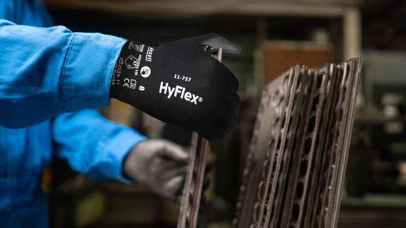 Operator wearing HyFlex® 11-757 mechanical gloves handles a glass sheet, ensuring safe grip and careful positioning during transport.