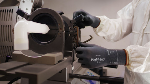 A worker wearing protective clothing and  HyFlex 11-840 mechanical glove adjusts knobs and components.