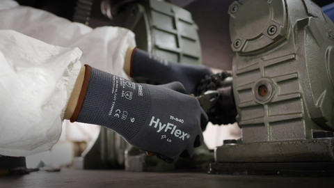A worker wearing protective clothing and  HyFlex 11-840 mechanical glove adjusts knobs and components.