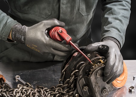 Worker wearing HyFlex® 11-939 mechanical gloves operates machinery, ensuring precision and safety in an industrial environment