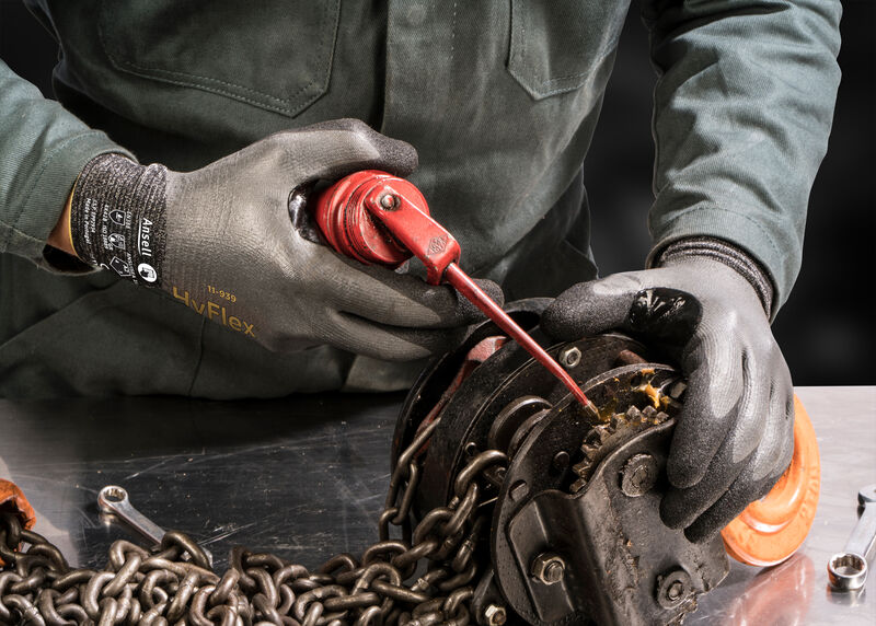 Worker wearing HyFlex® 11-939 mechanical gloves operates machinery, ensuring precision and safety in an industrial environment