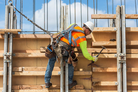 Worker wearing RINGERS® R665 mechanical gloves engages in house construction, handling materials with precision and care.