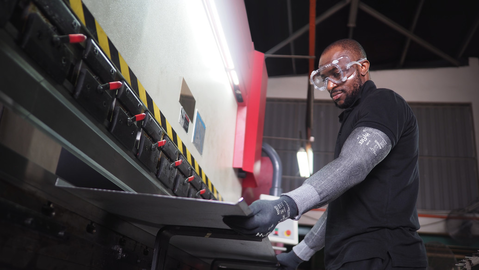 Operator wearing HyFlex® 11-280 sleeves handles a metal sheet, ensuring safe grip and careful positioning during assembling